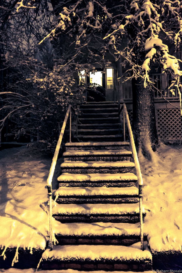Ein Gebäude mit einer schneebedeckten Treppe und Bäumen im Hintergrund.