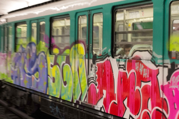 Ein Zug auf Schienen mit zwei Personen darin und Graffiti an der Außenseite.
