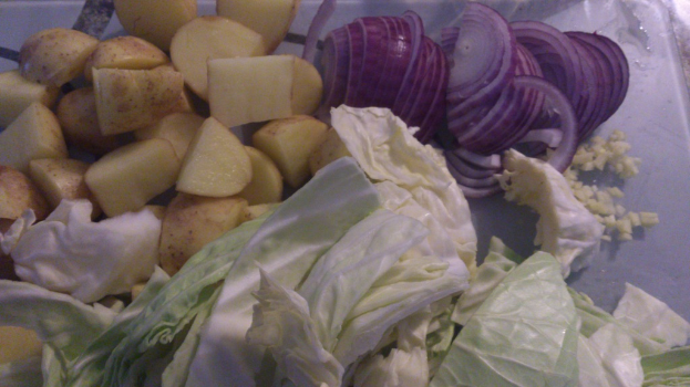 Ein Nahaufnahme von Zwiebeln, Kartoffeln und Kohlköpfen, die zusammen angeordnet sind.