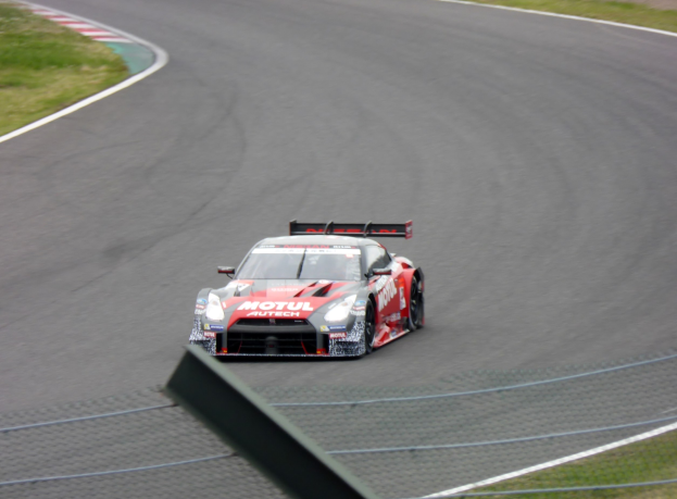 Ein Nissan GT-R Nismo GT3 Rennauto auf der Nürburgring 24 Stunden Strecke, flankiert von grünem Gras.
