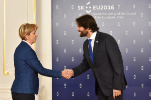 Bundeskanzlerin Angela Merkel und Bundespräsident Joachim Gauck geben sich die Hand vor einem "EU-Gipfel"-Plakat und lächeln freundlich.