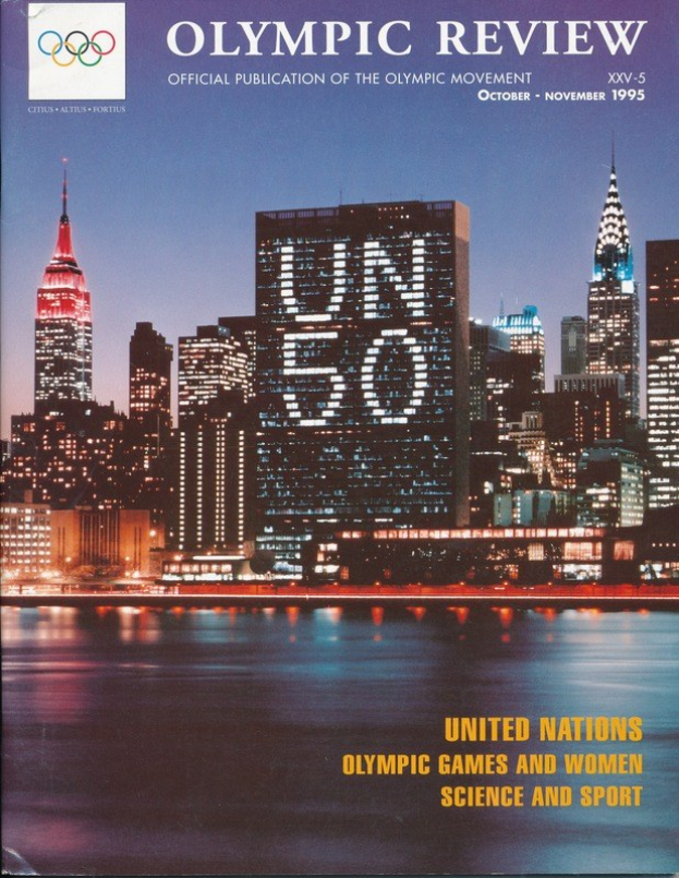 Buch mit dem Titel "Olympische Überprüfung Offizielle Veröffentlichung der Olympischen Bewegung" mit einem Stadtbild auf dem Cover, das auf einer flachen Oberfläche liegt.