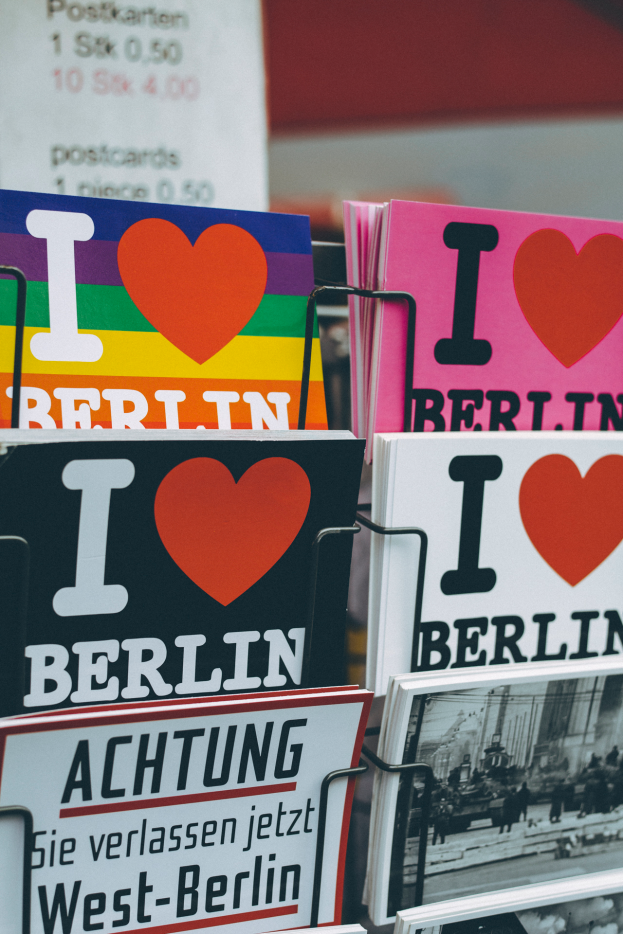 Ein Gestell mit verschiedenen Büchern und Plakaten mit der Aufschrift 'Ich liebe Berlin' vor einem unscharfen, träumerischen Hintergrund.