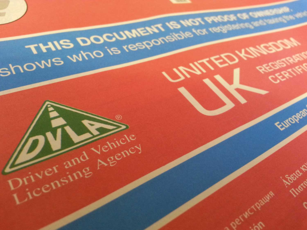 Ein Nahaufnahme eines roten und blauen britischen Führerscheins mit "DVLA" darauf.