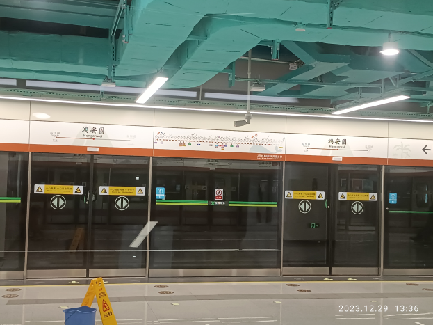 Eine U-Bahn-Station mit einem Schild, das aufgrund der COVID-19-Pandemie geschlossen ist, mit Glasdoors mit Schildern, einem Mülleimer, einer Warntafel auf dem Boden und Lampen und Rohren an der Decke.