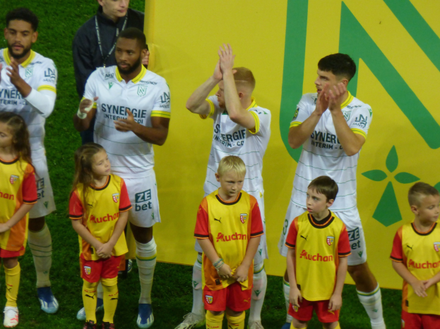 Gruppe von Fußballspielern in Uniformen, die auf einem Ligue 1-Feld nach einem Sieg klatschen