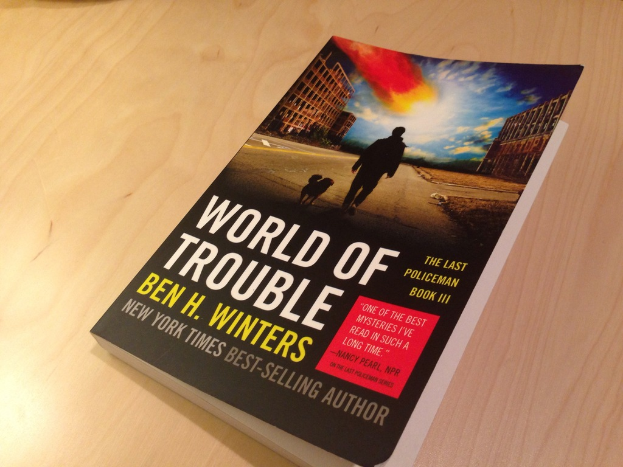 Ein Buch mit dem Titel "Welt der Probleme", das einen Mann und einen Hund auf dem Cover zeigt, auf einem Tisch.