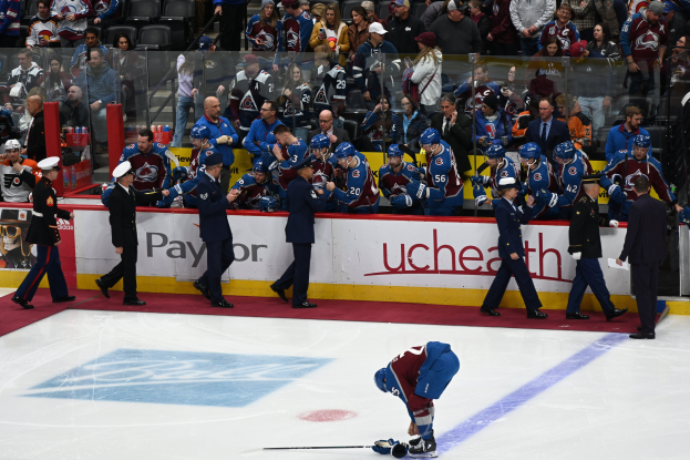 Hockeyspieler auf dem Eis umgeben von Menschen mit Mützen und Hockey-Schlägern, mit Zuschauern im Hintergrund und Tafeln mit "Colorado Avalanche vs San Jose Sharks - 3/24/15 NHL Pick, Odds, and Prediction".