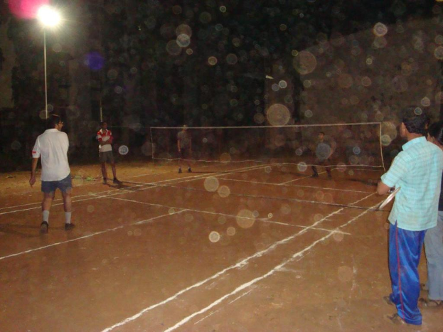 Eine Straßenlaterne an der linken Seite mit ein paar Männern, die Volleyball auf dem Boden spielen.
