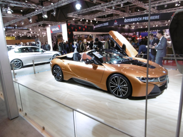 Ein BMW i8 Roadster auf der IAA in Frankfurt, ein schlankes, modernes Design mit glänzender schwarzer Lackierung und Chromakzenten, umgeben von Menschen in Abendgarderobe.