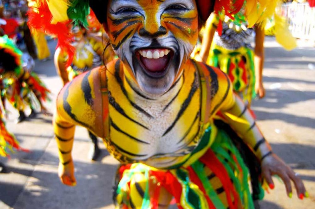 Eine Gruppe von Menschen in bunten Kostümen und Schminke, mit einer Frau im Tigerkostüm bei einem Karneval, mit einem unscharfen Hintergrund.