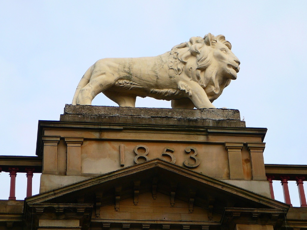 Eine Löwenstatue auf einem Gebäude mit der Inschrift 1853 darunter.
