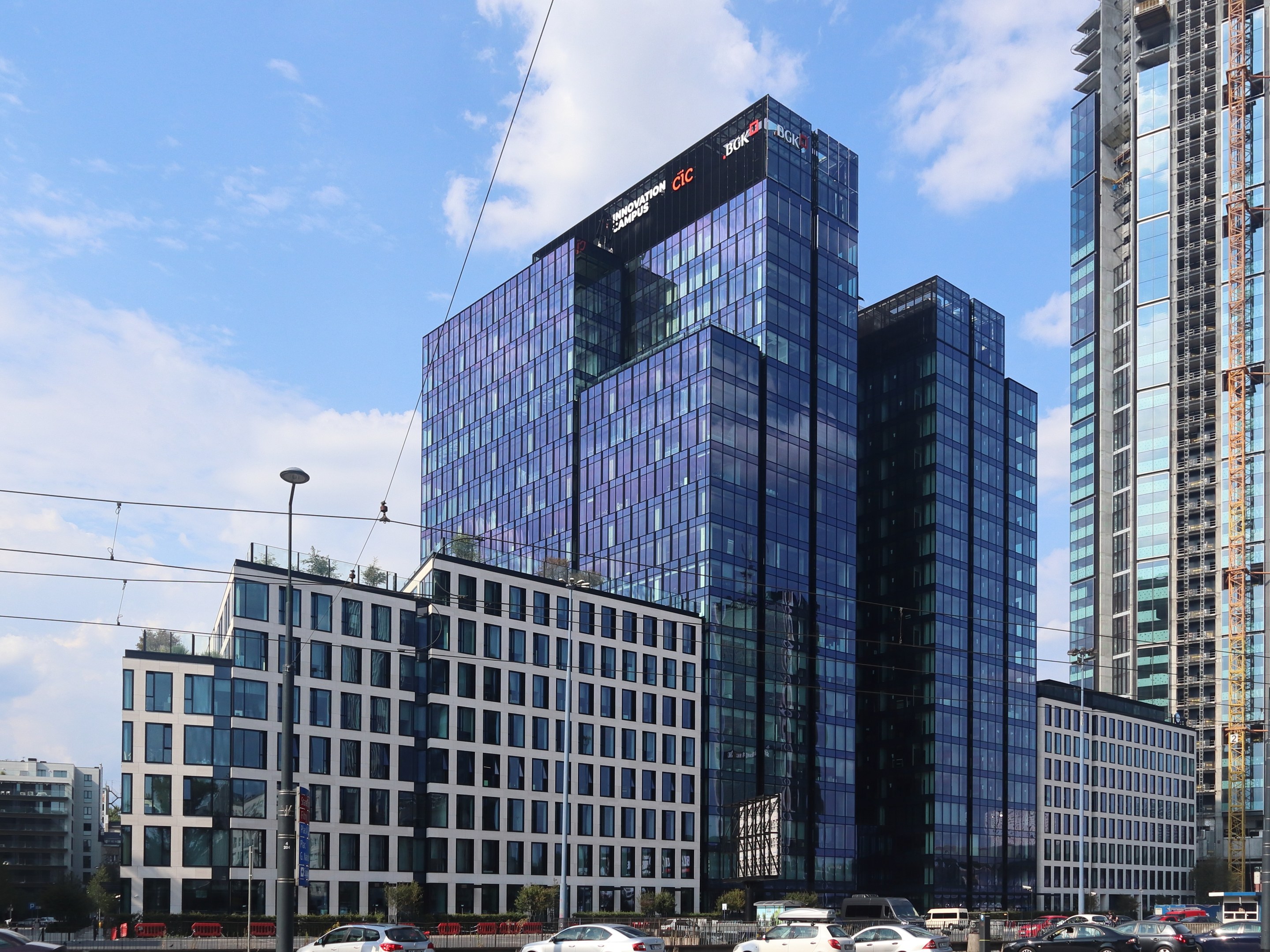 Zentrale der Deutschen Bank in Frankfurt, Deutschland, ein großes Gebäude mit vielen Fenstern, umgeben von städtischer Infrastruktur und Grünflächen unter einem bewölkten Himmel.