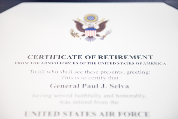 Rahmung des Ruhestandszertifikats der United States Air Force mit blauer Einfassung, das ein zentrales Sternschild-Logo zeigt, umgeben von einem Lorbeerkranz und einer 'Ruhestand'-Banderole, alles in schwarzer Tinte.