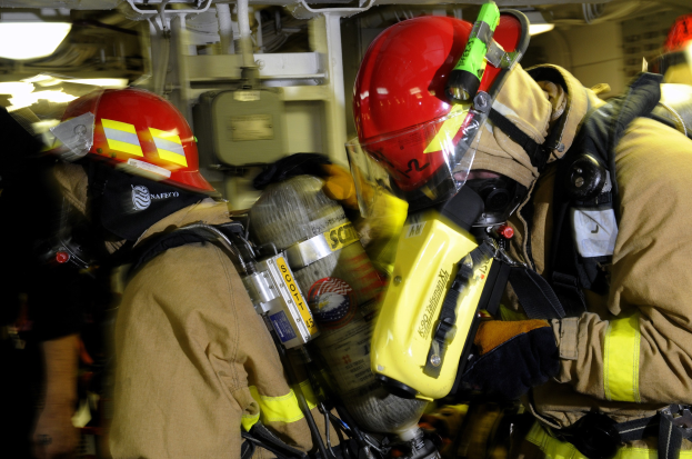 Feuerwehrleute in Schutzausrüstung arbeiten an einem Flugzeug während eines Trainings.