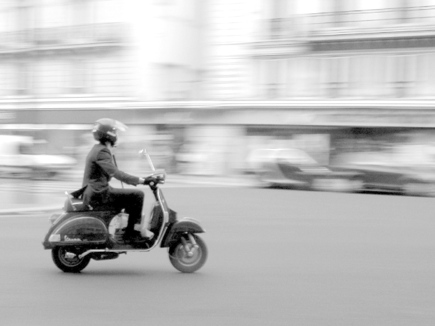 Eine Person, die ein Scooter auf einer Stra{ße} f"ahrt.