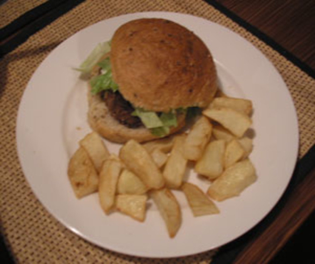 Ein Teller auf einem Tisch mit einem Burger und einer Portion Pommes.
