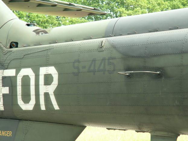 Nahaufnahme eines Militärhubschraubers mit der Aufschrift "FOR", umgeben von Bäumen im Hintergrund