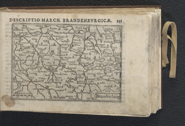 Offenes Buch mit detaillierter Karte von Brandenburgs geografischen Merkmalen auf schwarzem Hintergrund.