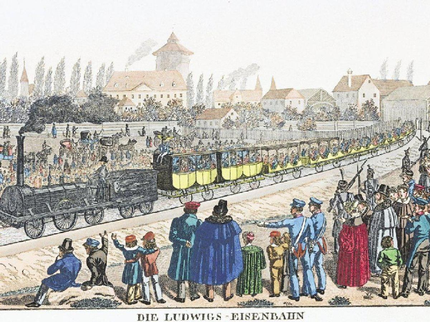 Gruppe von Menschen um einen Zug auf Schienen mit einigen Passagieren im Inneren und anderen draußen, mit Gebäuden und Bäumen im Hintergrund und Text 'Ludwigs-Eisenbahn, der erste Bahnhof in Deutschland' unten.