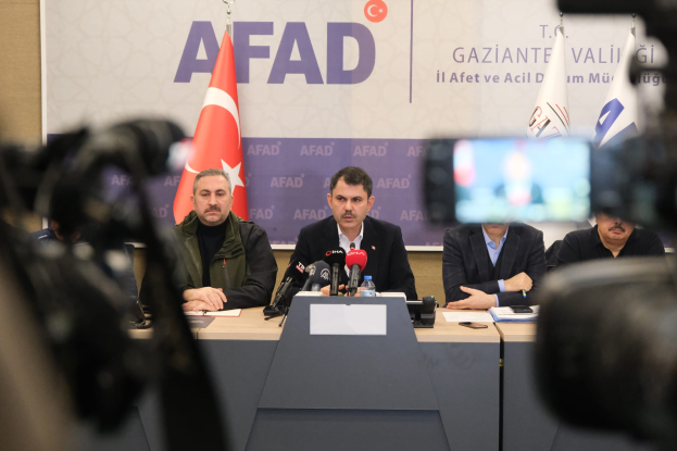 Eine Gruppe von Männern sitzt an einem Tisch mit Mikrofonen, Flaschen und Papieren, im Hintergrund Fahnen und eine Tafel mit der Aufschrift "AFAAD's statement on the situation in Turkey", und Kameras rechts daneben.