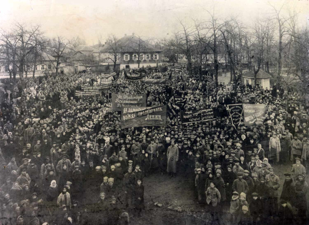 Eine große Menschenmenge mit Schildern steht vor einem Gebäude, mit Bäumen und Gebäuden mit Fenstern im Hintergrund, auf einem Schwarz-Weiß-Bild, das einen Protest gegen die Sowjetunion vermuten lässt.