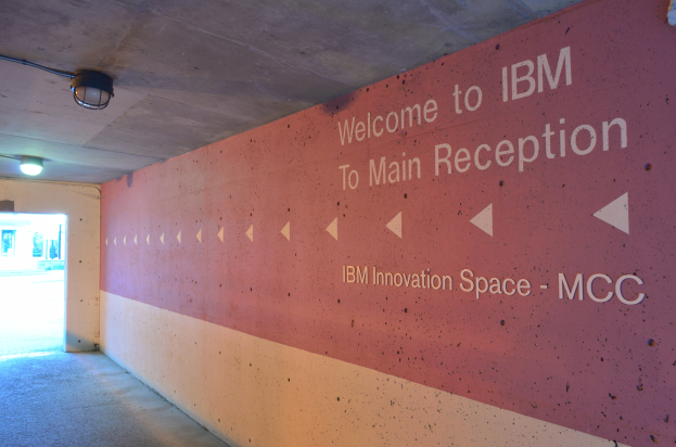 Eine Wand Mit Den Worten "Willkommen Bei IBM" Beleuchtet Durch Deckeneinbauleuchten, Mit Einer Tür Im Hintergrund Markiert "IBM Innovation Space MCC."