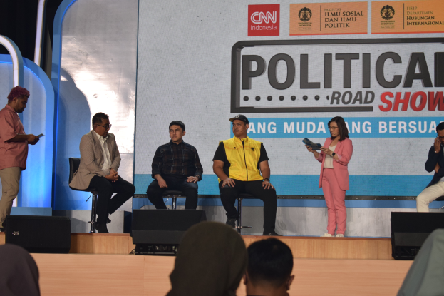 Eine Gruppe von Menschen auf einer Bühne sitzend mit einigen stehenden am Podium und einem Schild im Hintergrund mit der Aufschrift "Cnn Political Road Show."