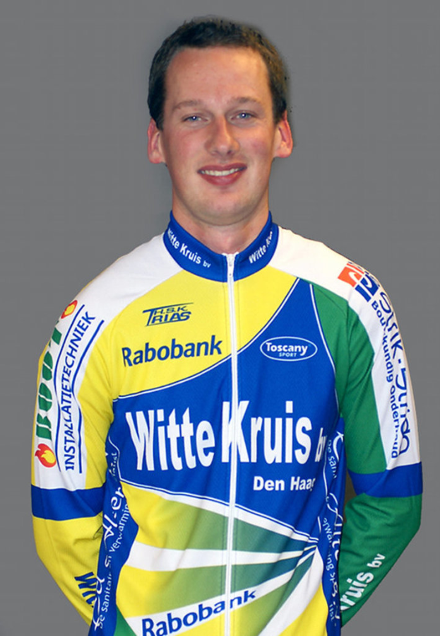 Ein Sportler posiert für ein Foto, trägt ein Trikot mit verschiedenen Sponsorennamen.