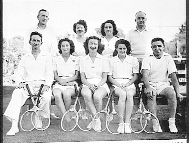 Schwarzes und weißes Foto einer Gruppe von Menschen, die auf einer Bank sitzen, lächeln und Tennisrackets halten, mit Bäumen und einem klaren Himmel im Hintergrund, mit der Aufschrift "Tennis Hall of Fame" unten.