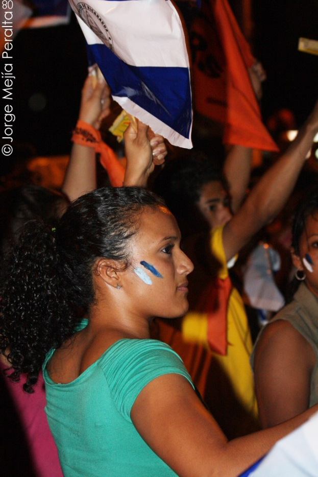 Frauen in grünen T-Shirts mit weißen Schildern auf einer Demonstration, mit mehreren anderen Mädchen dahinter.