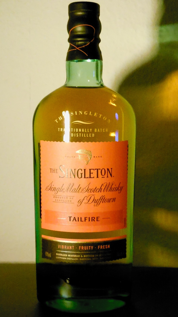 Eine tiefe Bernsteinflasche Singleton of Dufftown Tailfire Single Malt Scotch Whisky mit einem schwarzen Etikett, das ein Wappen mit einem Löwen und einer Burg zeigt.